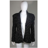 This Giorgio Armani jacket is composed of a wool blend in a black with white speckle textile print. There are front pockets, front button closures, and piping trim. In excellent condition. Made in Italy.