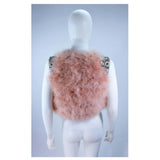 This Givenchy jacket is composed of a soft mauve pink marabou and features rhinestone jewel accents at the shoulders. The base is composed of silk and features a silk organza interior. In excellent condition.