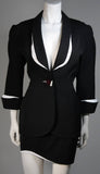 This fabulous Thierry Mugler ensemble is comprised of medium weight wool gabardine with a dramatic sculpted white lapel and cuff detail in white satin. Fitted waist has a single Tri-color abstract square button echoing the white edges of the lapels and cuffs. Medium density shoulder pads. Fitted skirt with a hidden zipper and covered satin snap at back with 3-D white detail at the hem.