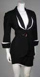 This fabulous Thierry Mugler ensemble is comprised of medium weight wool gabardine with a dramatic sculpted white lapel and cuff detail in white satin. Fitted waist has a single Tri-color abstract square button echoing the white edges of the lapels and cuffs. Medium density shoulder pads. Fitted skirt with a hidden zipper and covered satin snap at back with 3-D white detail at the hem.