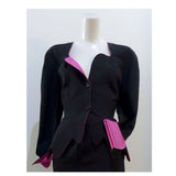 THIERRY MUGLER Black with Pink Lining and Cuff Skirt Suit Size 40. This THIERRY MUGLER skirt suit is composed of a black wool fabric with bright pink lining and cuff. Features a classic Mugler silhouette with nipped waist and curved bust-line to neckline design. The jacket has front snap closures, rounded shoulders, and a scalloped hem. The skirt features a zipper closure, flounce shape, and midi-length. In good vintage pre-owned condition. Made in France.Measurements in Inches:JacketBust: 40 Waist: 29 Skir