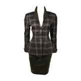This Thierry Mugler two-piece skirt suit is composed of a blue and grey plaid with faux leather. The jacket is accented by a quilted faux leather at the collar and cuffs. The skirt is composed of a black faux leather and features a pencil silhouette with zipper at the center back. This garment is excellent for design purposes, the collar is deteriorating (See photos). Made in France.