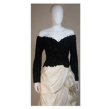 This Arnold Scaasi Couture gown is composed of a black velvet bodice fabricated from floral cut-outs and an off white tiered silk satin skirt. The gown has an off the shoulder style design with sweetheart neckline. There is a center back zipper closure and zippers at the sleeve end. In excellent vintage condition. 