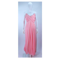ARNOLD SCAASI Pink Draped Chiffon Gown with Criss-Cross Bodice Size 4-6. This Arnold Scaasi gown is composed of a pink chiffon. The bodice has a criss-cross design. The skirt features a drape style. There is a center back zipper closure with bow accent. In very good condition with some minor fading.