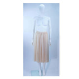 This Christian Dior Couture ensemble is composed of a raw silk chiffon in a natural nude hue. Features a peasant style blouse with ruffle and satin trim, there are side snap closures with hook and eyes. The skirt has a pleated style with side zipper closure.