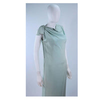 This Christian Dior gown is composed of an aqua crepe silk with as silk satin slip. Features an asymmetrical design with a side zipper. In excellent vintage condition, there are some signs of wear due to age. 