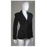 This Giorgio Armani jacket is composed of a wool blend in a black with white speckle textile print. There are front pockets, front button closures, and piping trim. In excellent condition. Made in Italy.