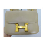 HERMES Camel Constance Crossbody Bag. This Hermes leather bag features a gold H closure, gold hardware, and a bone top stitch. Made in France. Measurements in Inches: Length: 9 Height: 7 Width: 2 Strap single: 32 Strap doubled: 19