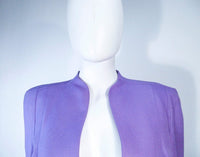 This Thierry Mugler skirt suit is composed of a lavender/purple hue fabric. Features a classic Mugler silhouette with nipped waist and curved bust-line to neckline design. The classic pencil style skirt features a zipper closure. In good vintage pre-owned condition (some signs of wear due to age) the skirt shows signs of alterations. Made in France.