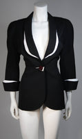 This fabulous Thierry Mugler ensemble is comprised of medium weight wool gabardine with a dramatic sculpted white lapel and cuff detail in white satin. Fitted waist has a single Tri-color abstract square button echoing the white edges of the lapels and cuffs. Medium density shoulder pads. Fitted skirt with a hidden zipper and covered satin snap at back with 3-D white detail at the hem.