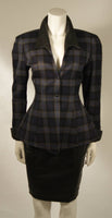 This Thierry Mugler two-piece skirt suit is composed of a blue and grey plaid with faux leather. The jacket is accented by a quilted faux leather at the collar and cuffs. The skirt is composed of a black faux leather and features a pencil silhouette with zipper at the center back. This garment is excellent for design purposes, the collar is deteriorating (See photos). Made in France.