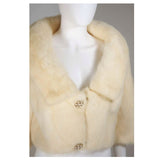 This Oleg Cassini jacket is composed of an off-white/cream hue mink. Features large rhinestone and faux pearl buttons. In excellent vintage condition, the lining does have some discoloration due to age. 