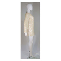 This Oleg Cassini tunic is composed of an off-white iridescent sequined silk. Features side slits with white beading embellishment, there is a center back zipper closure. In great vintage condition. 